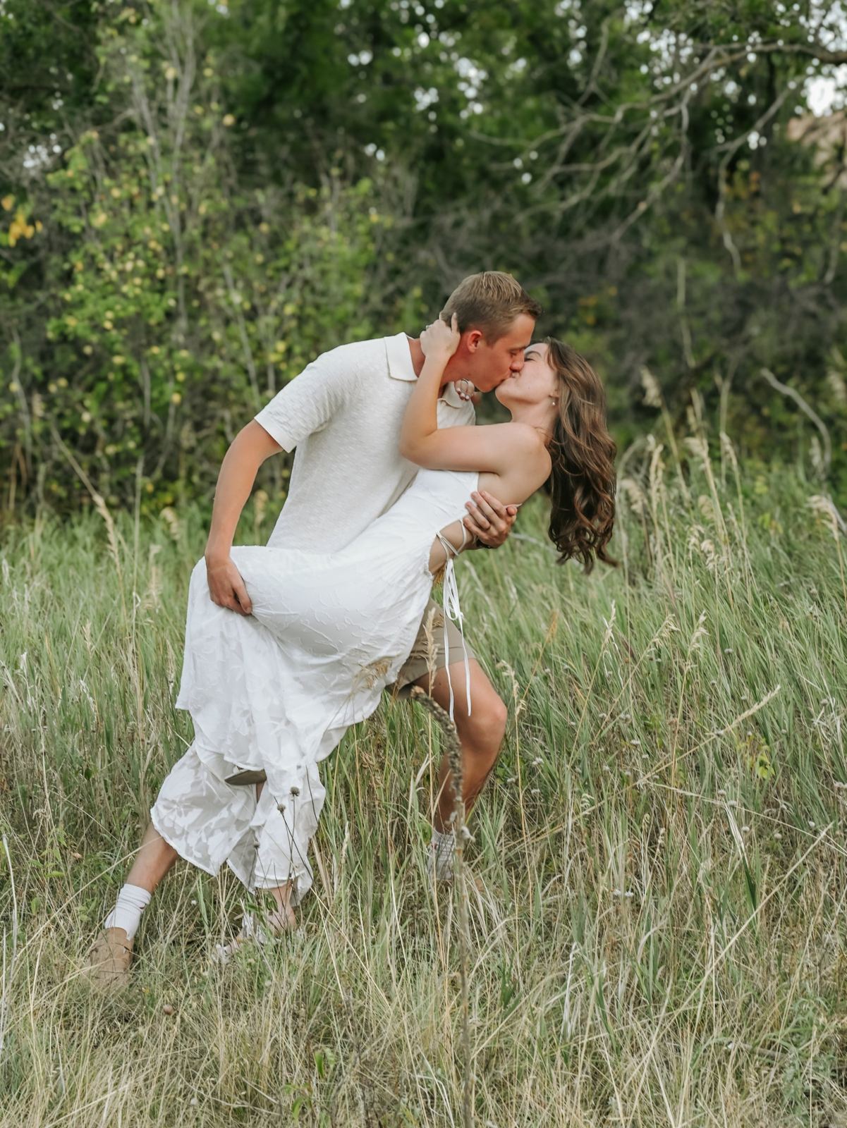 Jacob dipping Angela for a kiss in a field of tall grass